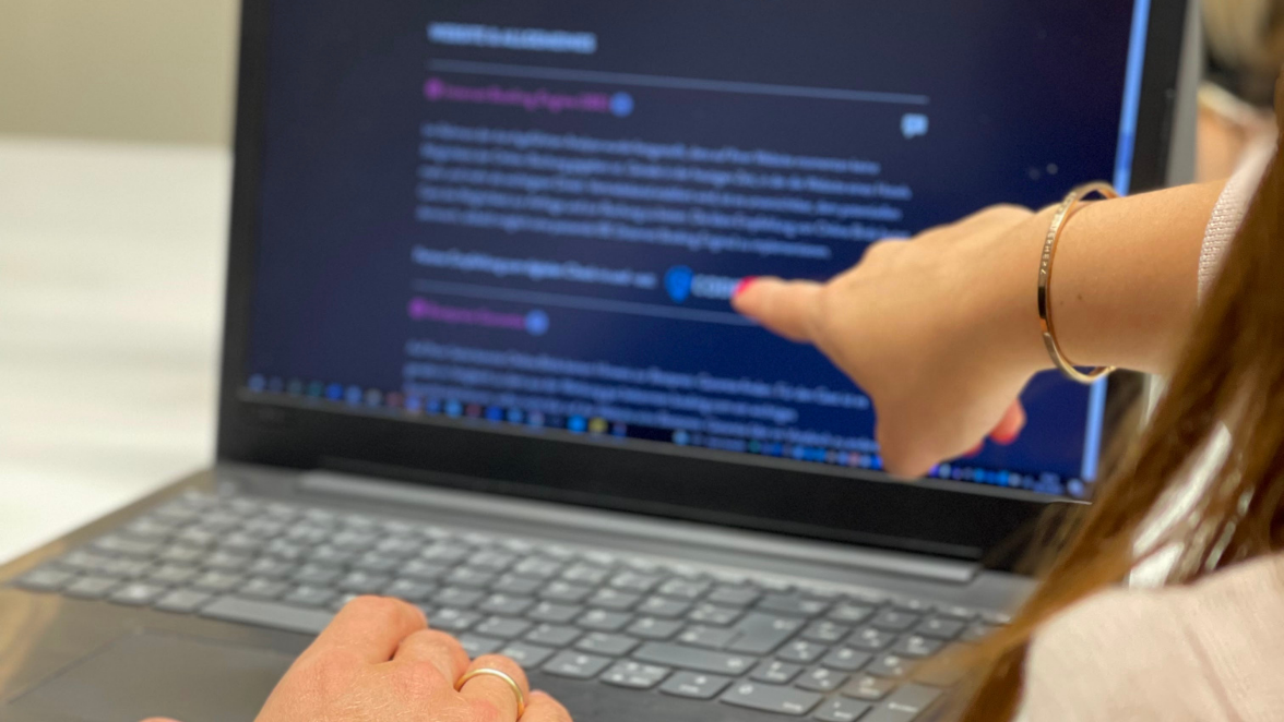 Frau mit einem goldenen Armreifen die auf einen Laptop zeigt