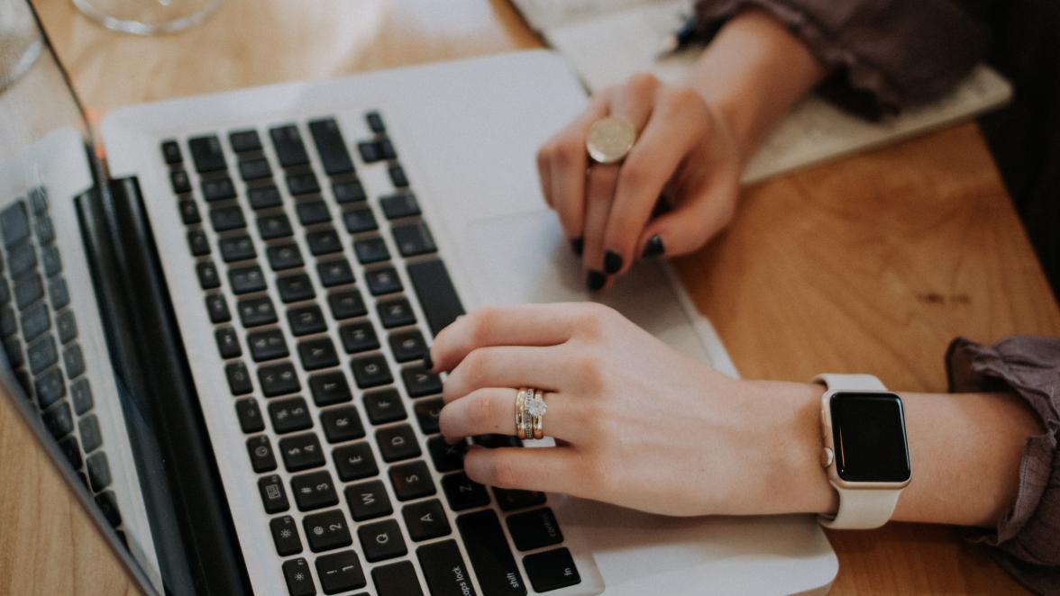 Frau mit viel Handschmuck, die an ihrem Laptop arbeitet