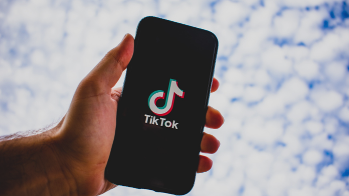 Mann der ein Handy mit dem Symbol der TikTok App in den Himmel hält